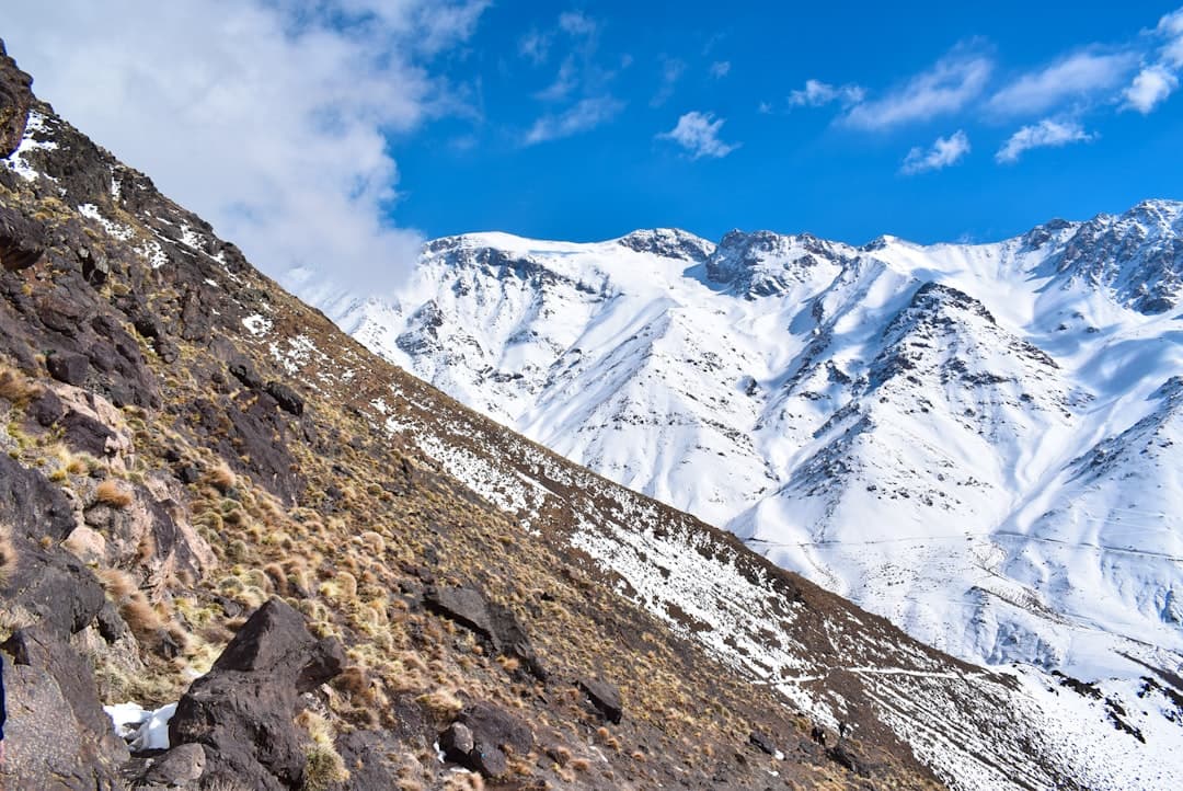 Toubkal in winter β climbers in crampons ascending the snow-covered summit cone of North Africa's highest peak under a blue alpine sky