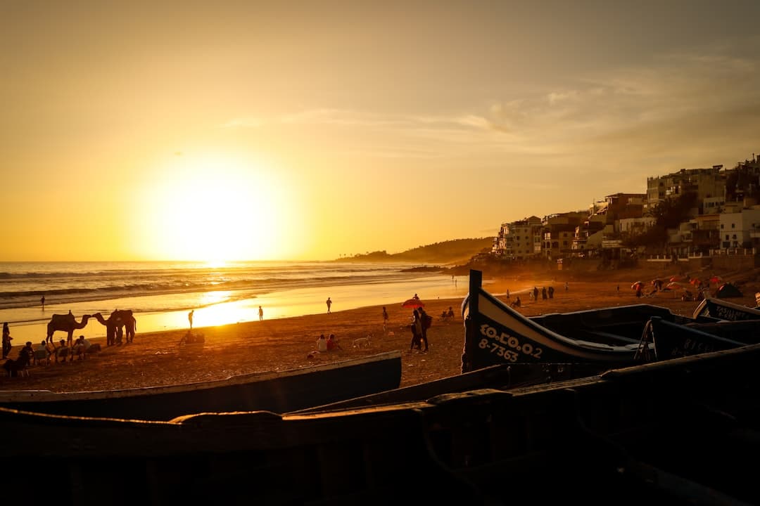 Taghazout vs Essaouira surf — a clean right-hand point break beside a windy kite-dotted beach on Morocco's Atlantic coast